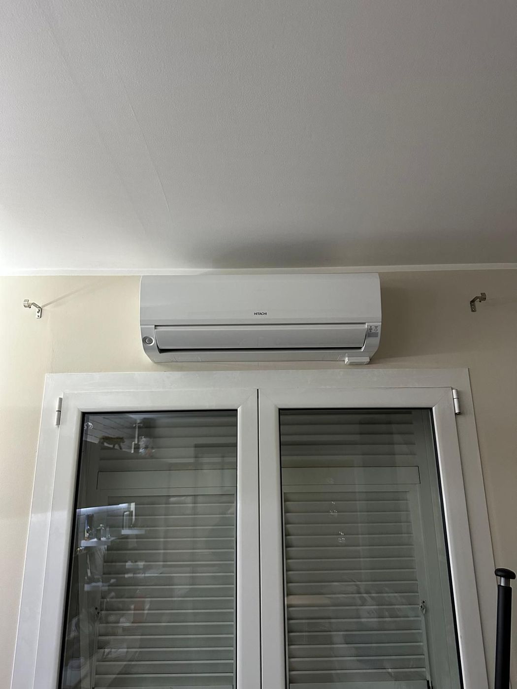 Unité intérieure de climatisation murale posée au-dessus d'une porte-fenêtre