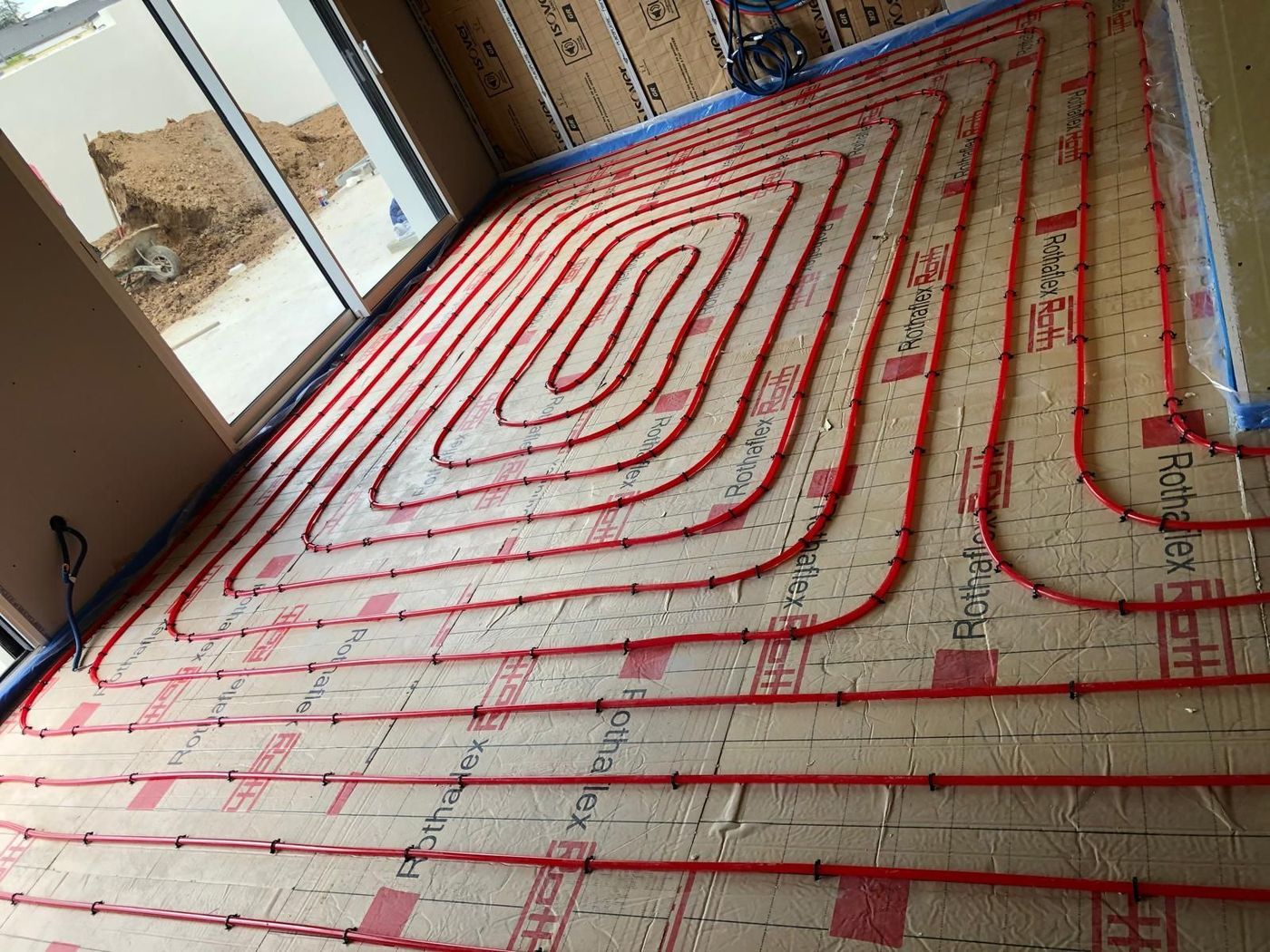 Réseau de plancher chauffant posé avant la chape, raccordé à une pompe à chaleur