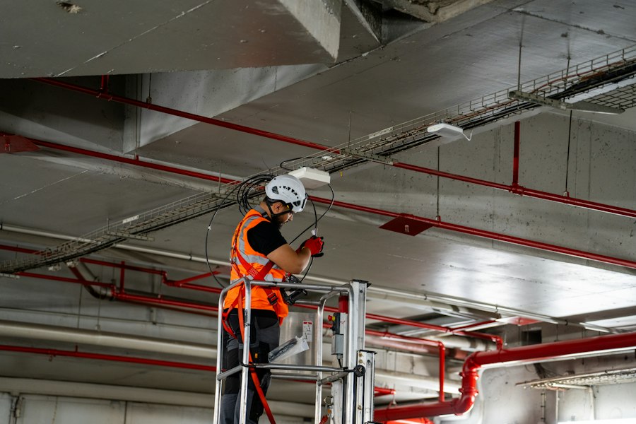 Technicien sur nacelle installant des équipements de climatisation au plafond d'un local professionnel